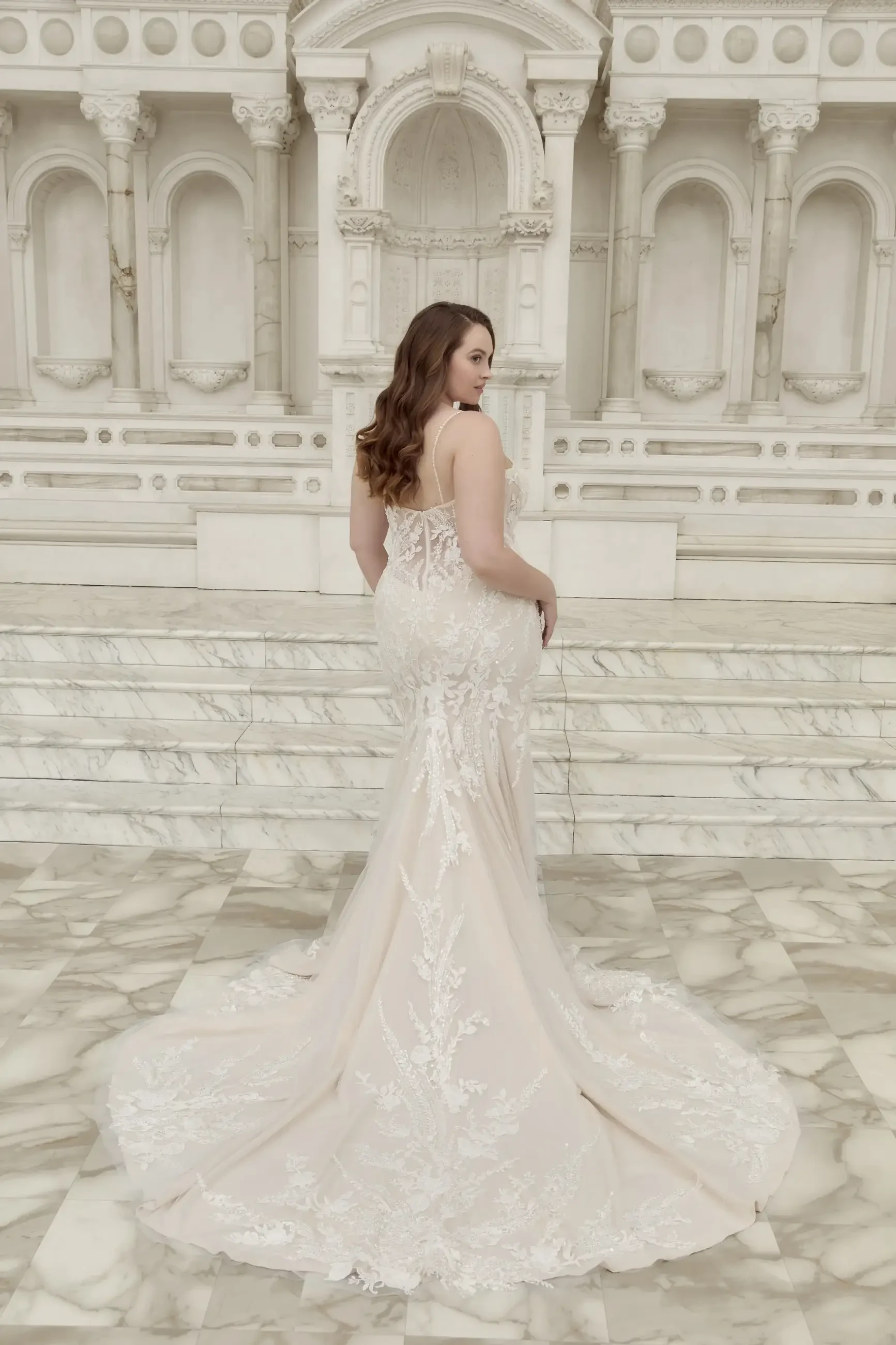 model is wearing a plus size fit and flare lace bridal gown
