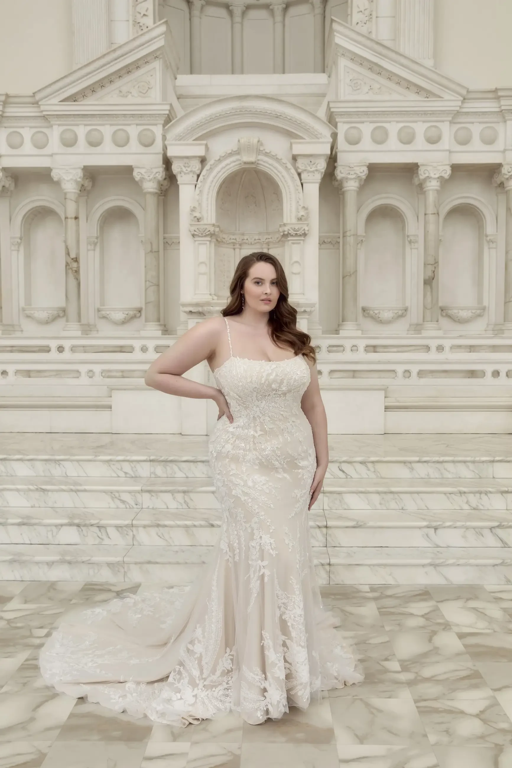 model is wearing a plus size fit and flare lace bridal gown