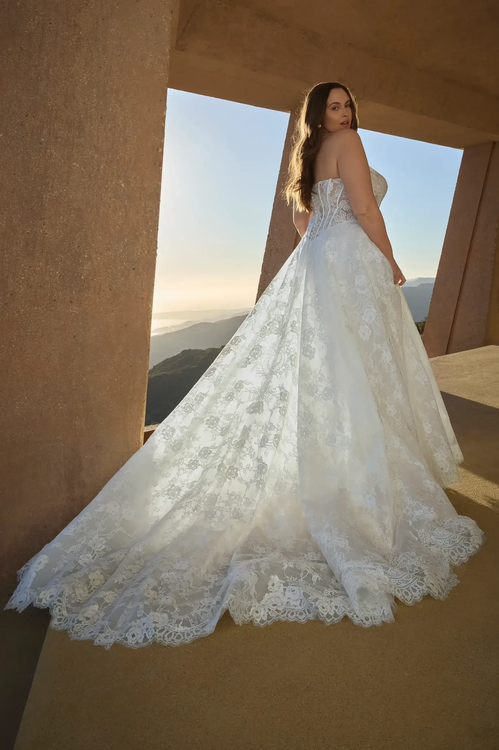 model is wearing a plus size strapless basque waist wedding dress