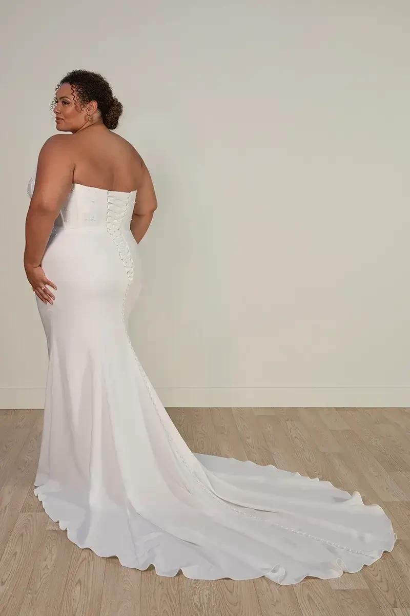 model is wearing a strapless plus size sheath wedding dress