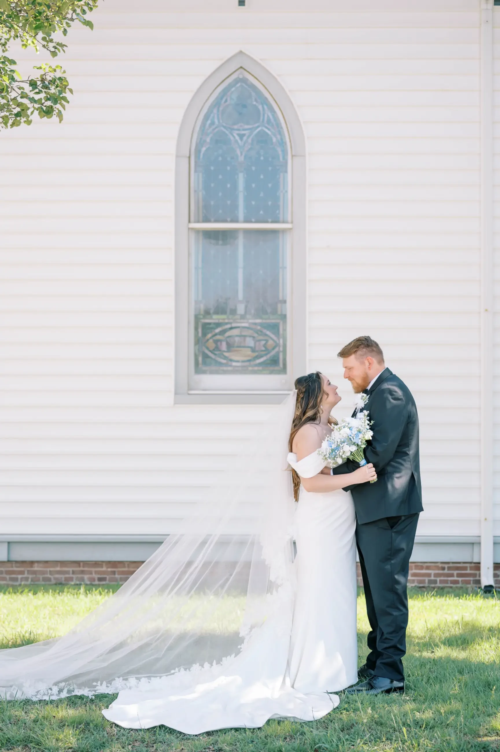 Virginia and James hugging, looking into each other’s eyes, with Virginia in her Serendipity Bridal gown.