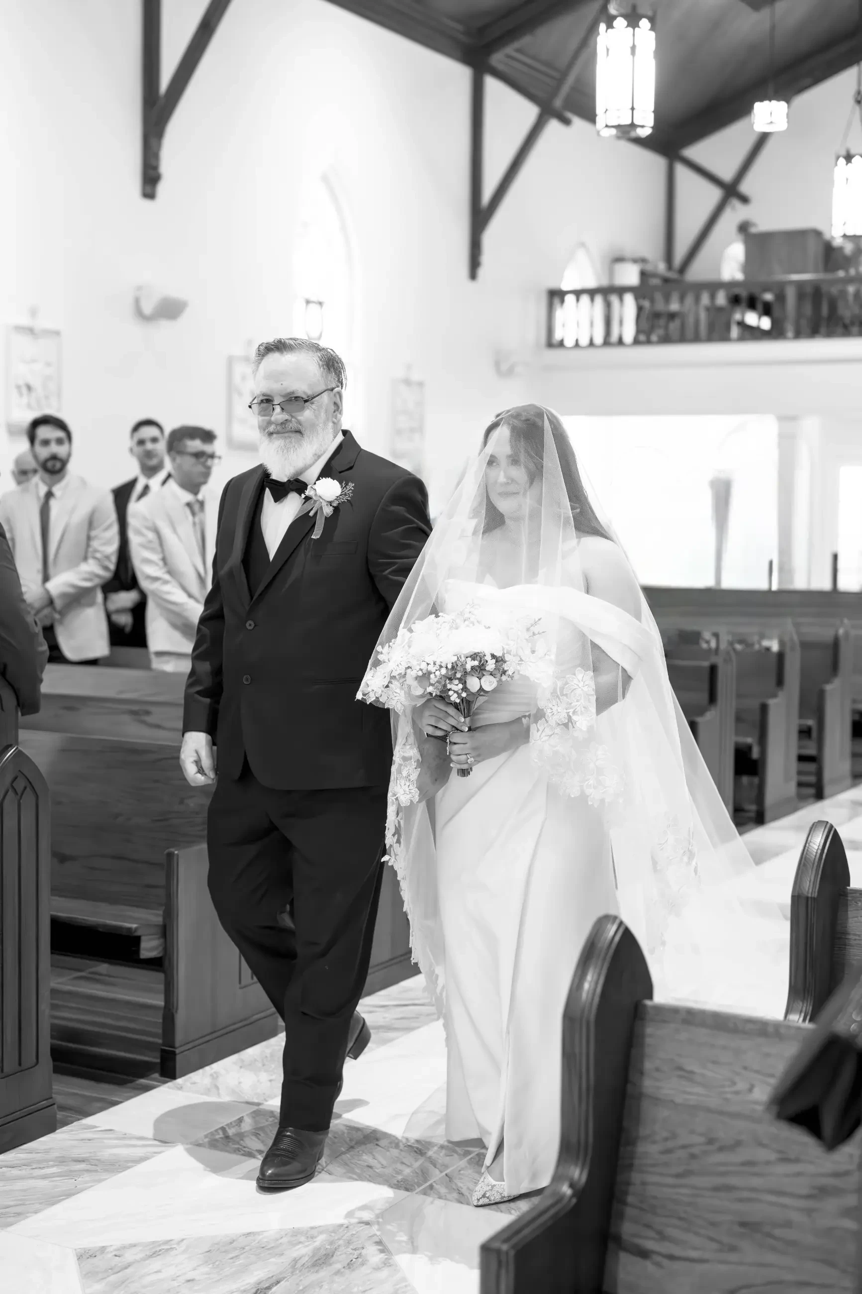Virginia walking down the aisle with her father, wearing her gown from Serendipity Bridal.