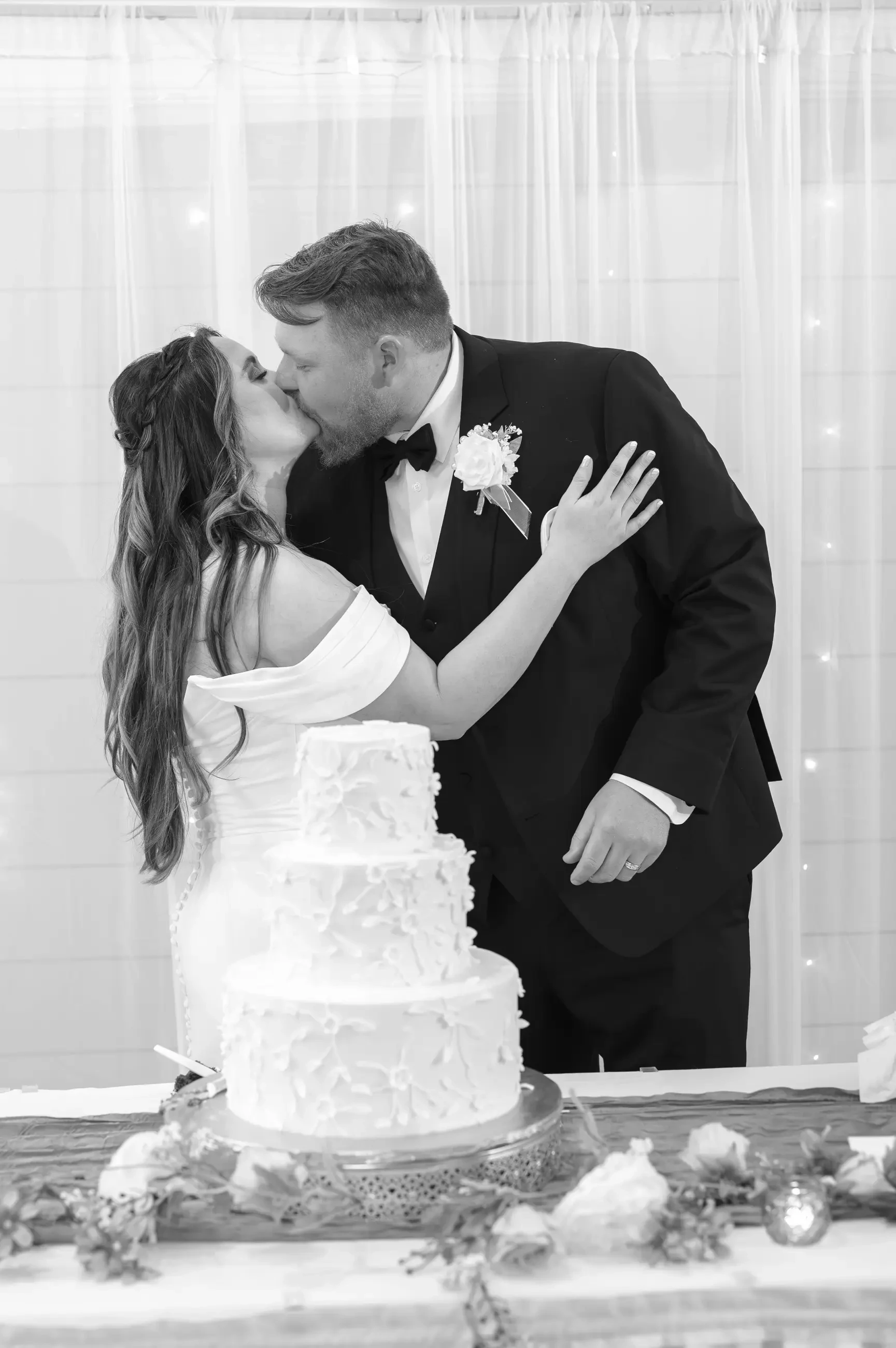 Virginia and James kissing behind the wedding cake.