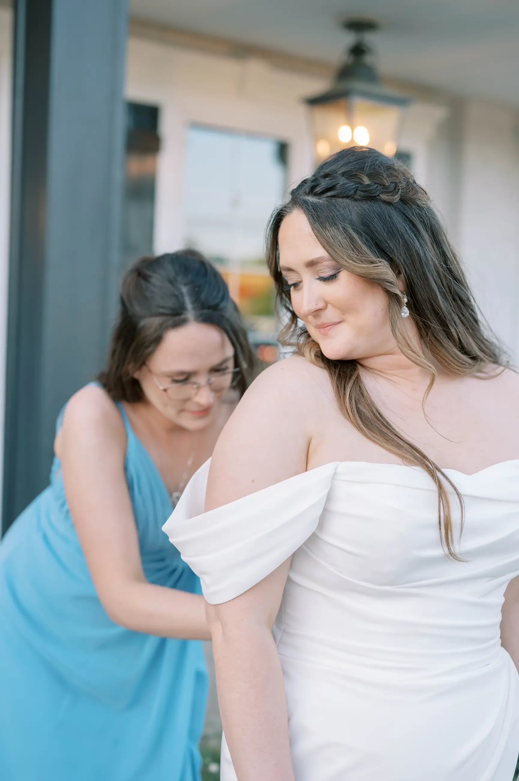 A bridesmaid helping Virginia with her wedding dress.