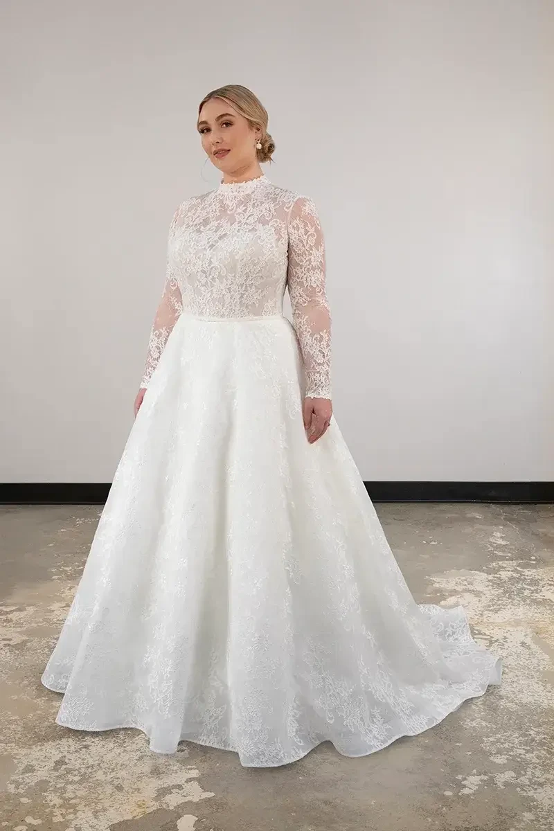 model is wearing a plus size high neckline ball gown wedding dress with an open back