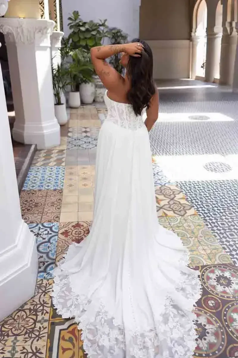 A person in a white dress with intricate lace detailing is seen from the back, standing on a colorful tiled floor.